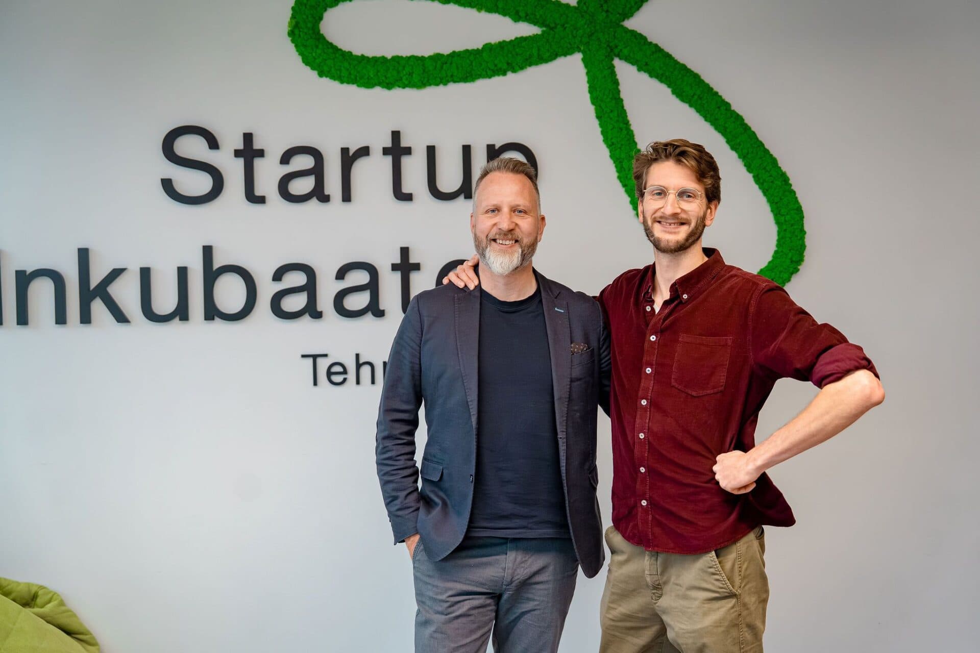 Simon and Ben, Askara Solutions co-founders, posing in front of the Startup Inkubaator Tehnopol sign with its green decorative knot logo